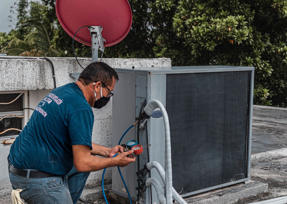 Technician checking manifold gauges on an AC unit